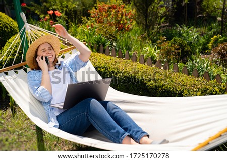 businesswoman freelancer in hat lies in the hammock and working on the computer, answering phone call, makes a selfie photo. Remote working, isolation in quarantine. the social distance.