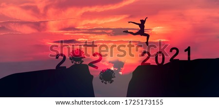 Young woman Jumping across the gap of the mountain from 2020 to 2021 New Year. 
 Royalty-Free Stock Photo #1725173155