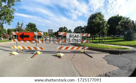 Road Closing and Detour signs blocking road during an event with Police cars and people walking in the distance in summer under pretty sky