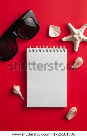  Tropical background. Flatlay with starfish, shells, white blank notebook, Sunglasses on a red background. The concept of travel, vacation by the sea. Copy space