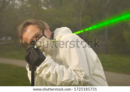 Criminologist technician in protective suit and mask working with ballistics laser Royalty-Free Stock Photo #1725185731
