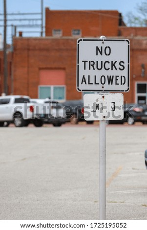 A sign at a parking lot entrance stating no trucks are allowed