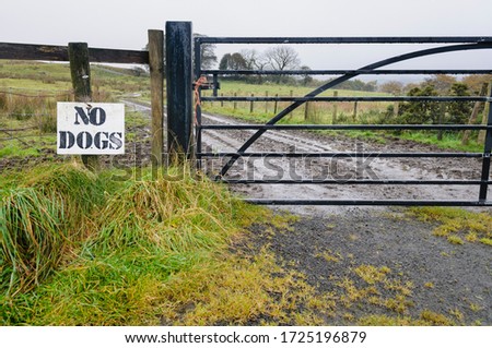 Sign on a fence around a field saying "No Dogs" to prevent people hunting