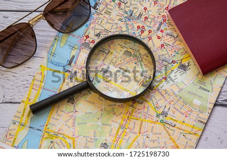 Magnifying glass, sunglasses and map on the wooden background. Flat lay traveler accessories. Top view travel concept with maps and magnifying glass. 