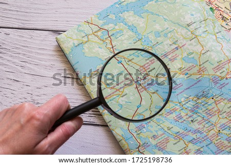 Magnifying glass and ancient map on the wooden background. Hand holding a magnifying glass over the map.