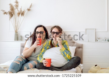 Cute children in 3d glasses watching movie on the bed at home.Eat popcorn. Family concept, no gadgets. happy mom and kids.