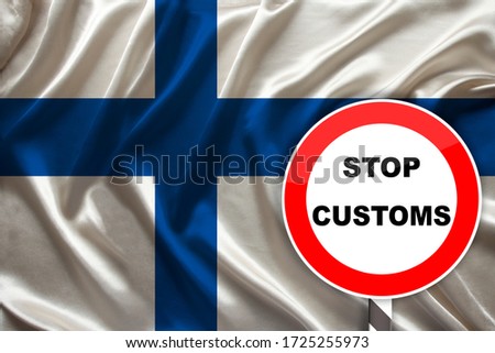 customs sign, stop, attention against the background of the silk national flag of Finland, the concept of border and customs control, violation of the state border, tourism restrictions