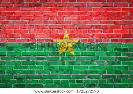 National flag of Burkino Faso  depicting in paint colors on an old brick wall. Flag  banner on brick wall background.