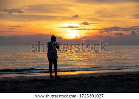 Tourist take photos of the sunset view.Silhouette picture style at Mae Ramphueng Beach in Rayong Province of Thailand.