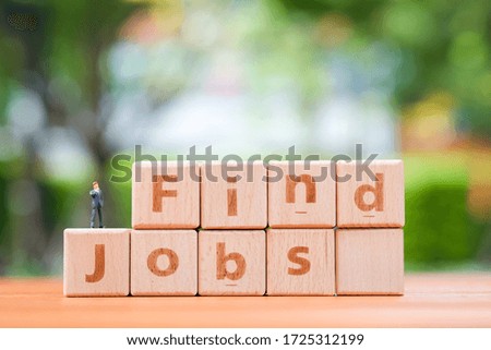 Miniature business man on wooden block with word Find Jobs. Search job and Human Resources concept.