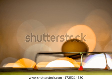 A blurry abstract background of bokeh lights falling onto a hen's egg with a small frying basket placed on a wooden floor.