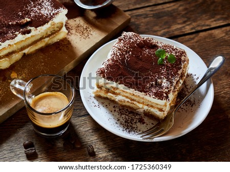 Large portion of fresh Italian tiramisu dessert served on a plate at table with espresso coffee alongside in a high angle view suitable for a menu Royalty-Free Stock Photo #1725360349