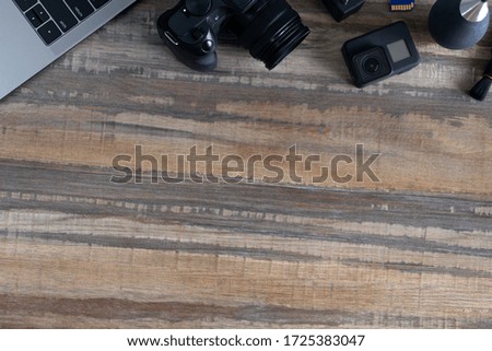 Flat lay of photography equipment on wooden desktop background: dslr camera and lens. Photographer workspace concept. Copy space, top view