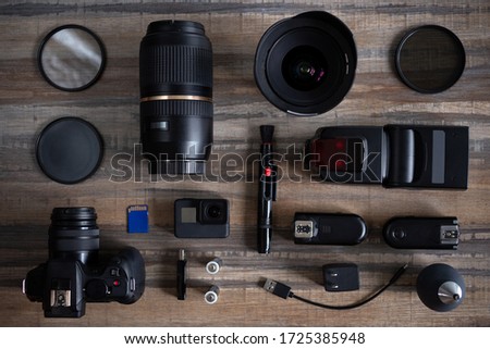 Flat lay of photography equipment on wooden desktop background: dslr camera and lens. Photographer workspace concept. Top view