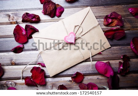 Image of letter of love with small pink heart surrounded by rose petals
