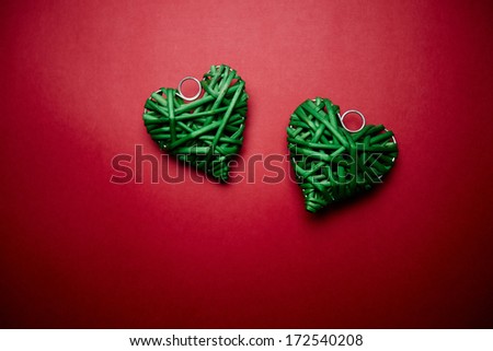 Image of two decorative green wattled hearts on red background