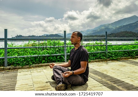man meditating at beautiful lake hiking trails with mountain background from unique perspective