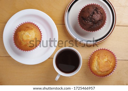 Chocolate and vanilla muffins and cup of coffee on wooden table, top view