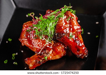 American cuisine. Juicy fried chicken wings glazed with sesame seeds and herbs. Beautiful serving dish in a restaurant in a black plate. background image, copy space text