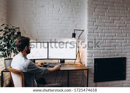 stylish man working with a computer on two monitors, designer or professional visualizer working on a project at home Royalty-Free Stock Photo #1725474658