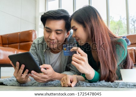 Young couple use credit card for online shopping on internet website at home. Number on the credit card is mock up. No personal information shown on the credit card. Online business shopping concept.