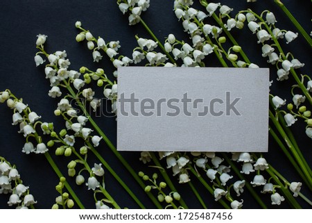 Mockup with 
business card lily of the valley on black table. background with copy place