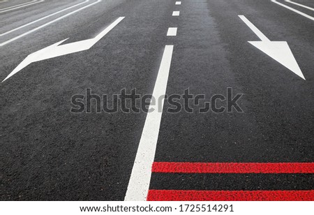 White road marking lines and red rumble strips on the road. Arrows on the road. 