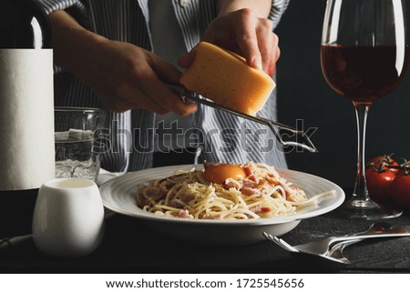 Woman grating cheese on pasta. Cooking pasta composition