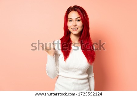 Teenager red hair girl isolated on pink background pointing to the side to present a product