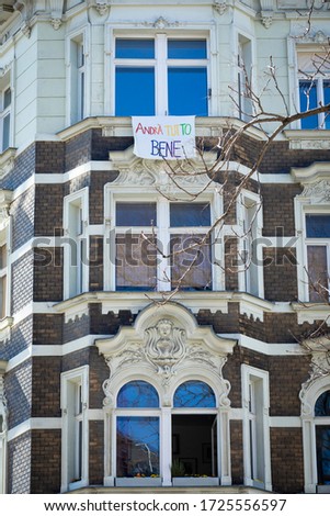 a banner ribbon with the message: Andra tutto bene",is hanging on  a beautiful art deco facade in Vienna