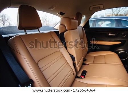 Luxury car interior made of yellow leather. Leather folding armrest armrest with cup holders in rear seats inside a vehicle. Clean leather interior: yellow rear seats, headrests and belts. Royalty-Free Stock Photo #1725564364