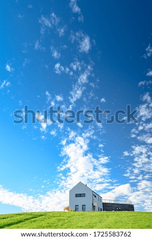 Modern house on green meadow. Blue sky, edit space. Architecture photo.