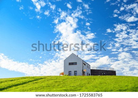 Modern house on green meadow. Blue sky, edit space. Architecture photo.