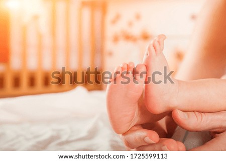 Legs of a newborn in hands closeup. Baby's feet and copy space. Infant care and colic