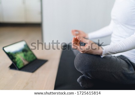 Woman meditates in front of tablet close-up