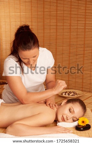Beautiful young woman having a massage treatment in spa salon - wellness .