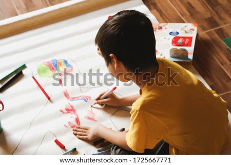 A child sits on the floor and paints a full-length human organs drawn on a large sheet