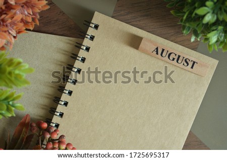 Cover of August month with notebook on table.