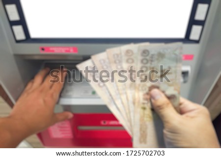Abstract blurred photo Close up withdraw bank notes in the hand of five thousand baht from the ATM.unemployment benefits after filing a claim concept.