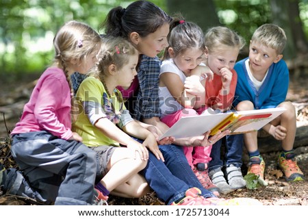 Kindergarten teacher reading with kids in a wood kindergarten Royalty-Free Stock Photo #1725713044