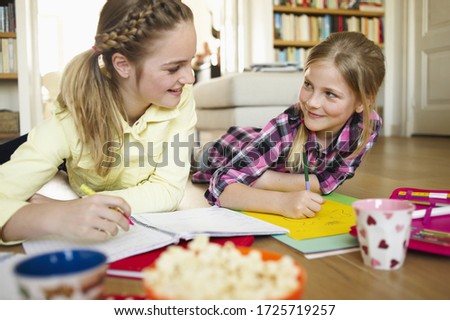 Two young girls coloring and doing homework together