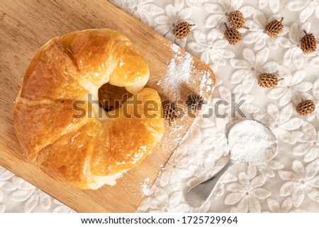 Picture from the top of the croissant placed on a wooden chopping block placed on a white lace