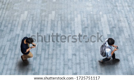 Human life in Social distance. Aerial top view with blur man with smartphone walking converse of other people at pedestrian on white grey paint texture on background. with empty space.
