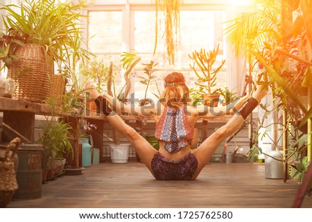 A young woman practices yoga among the urban jungle. Girl in yoga asanas and Pilates at home close-up and copy space.