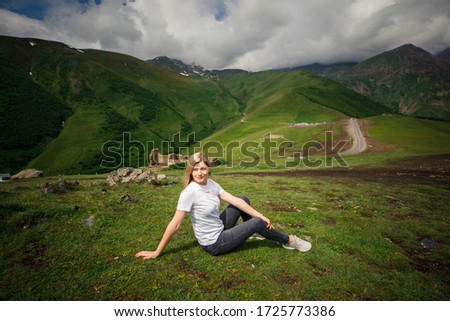 young beautiful girl with a blonde in a white t-shirt sits on a background of mountains in Georgia