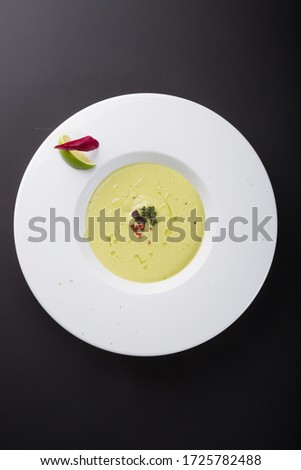 Green creamy avocado soup with lime in white bowl plate