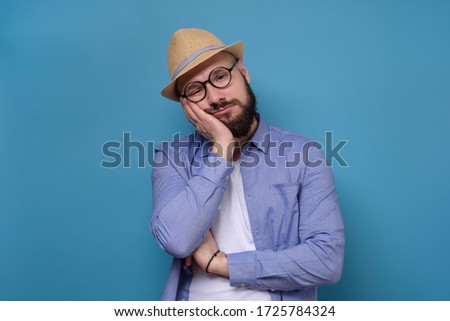 I am tired of everything. Bored man is tired to listen to his girlfriend hysteria and demands. Studio on trendy blue background