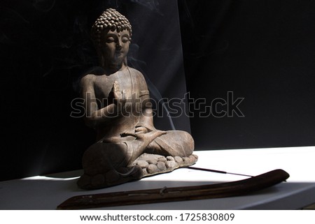 Buddha statue with incense stick into sun light on black background mental health home time self care concept