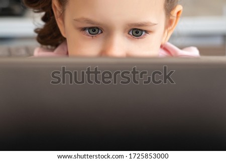 A close up of a little girl looking at a laptop or tablet with copy space