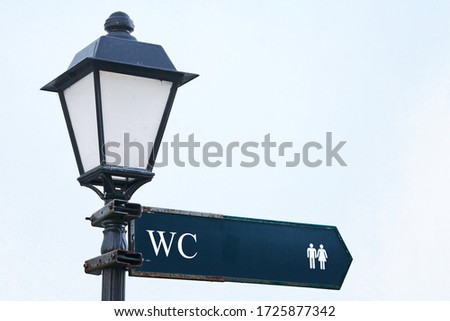 Public toilet, wc or restroom sign on vintage street light pillar. Street lamp with wc symbols
